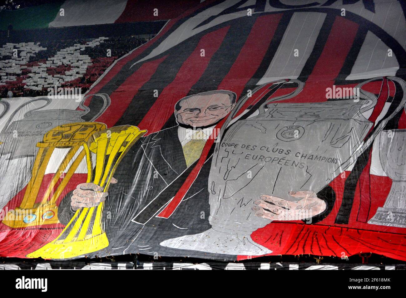 Fußballfans des AC Mailand zeigen eine Koreographie mit dem Präsidenten Silvio Berlusconi, der im Stadion San Siro in Mailand, Italien, eine Trophäe hält. Stockfoto