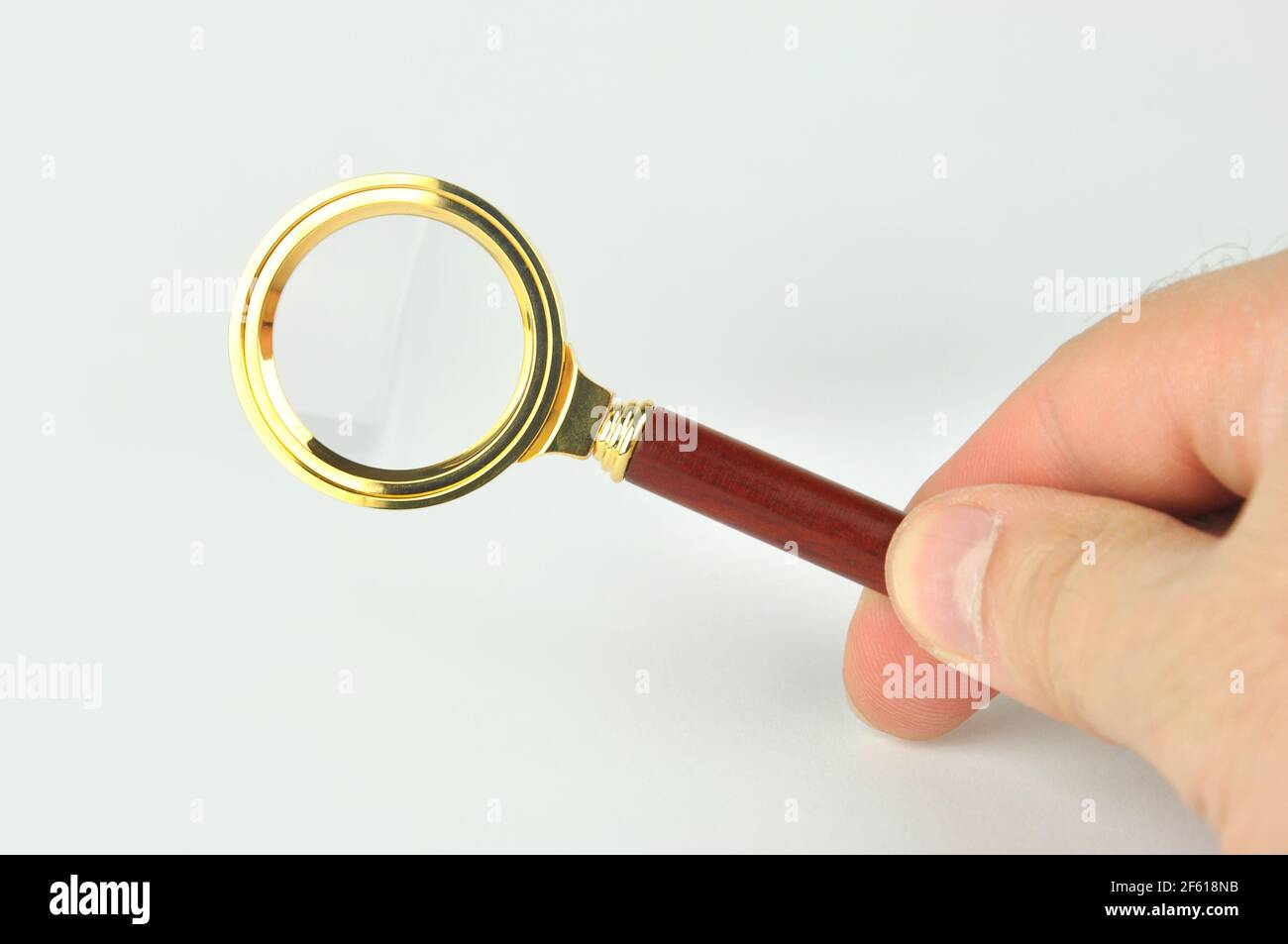 Lupe in männlicher Hand auf grauem Hintergrund. Konzeptanalyse, Suche, Recherche und Untersuchung. Stockfoto
