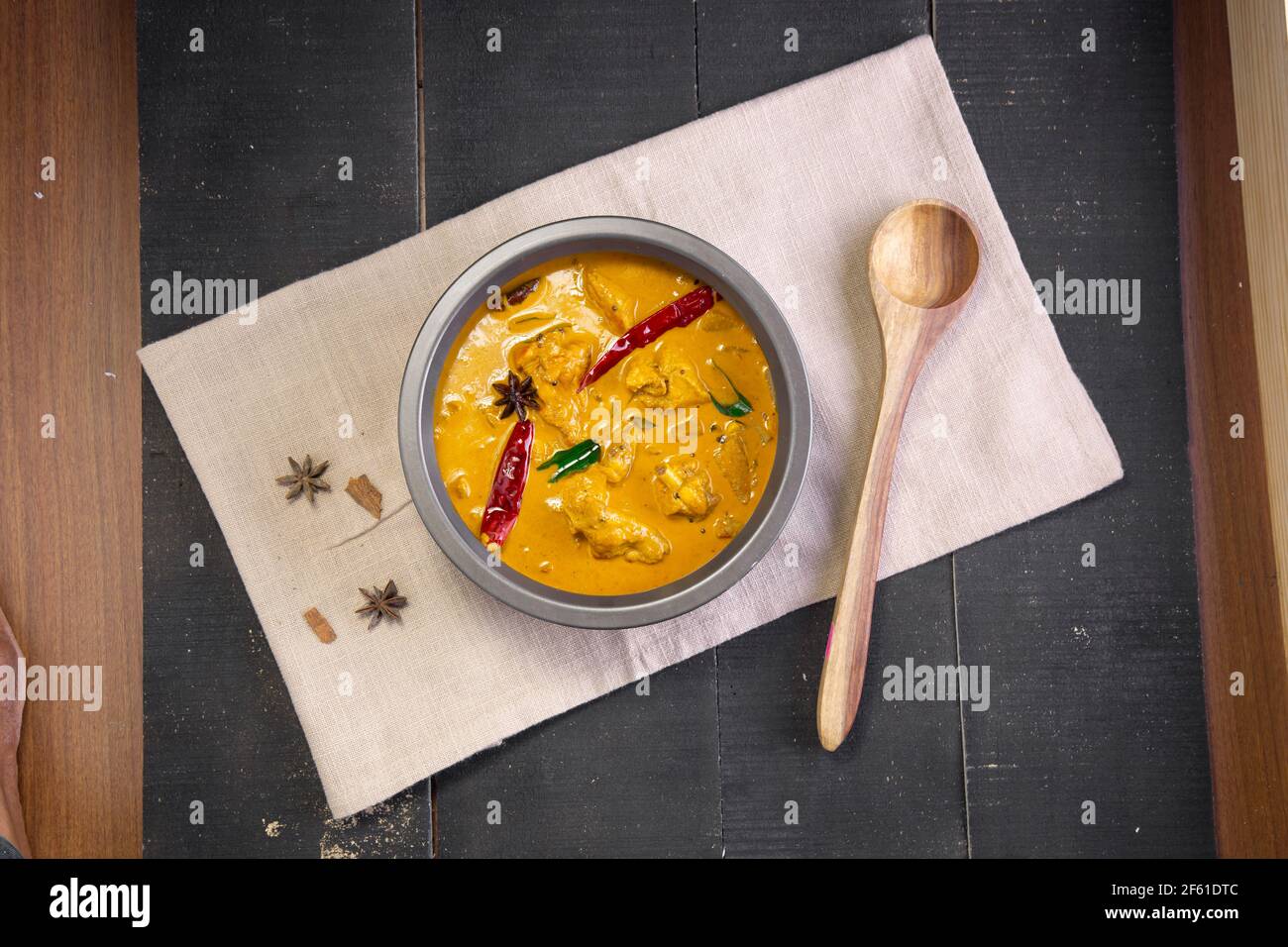 Huhn mit rohem Bananencurry (Kochbananen), würziges Huhn mit grüner Banane Schmackhaferes indisches Gericht in einem Geschirr, das auf ist angeordnet Ein Gewebe mit schwarzem b Stockfoto