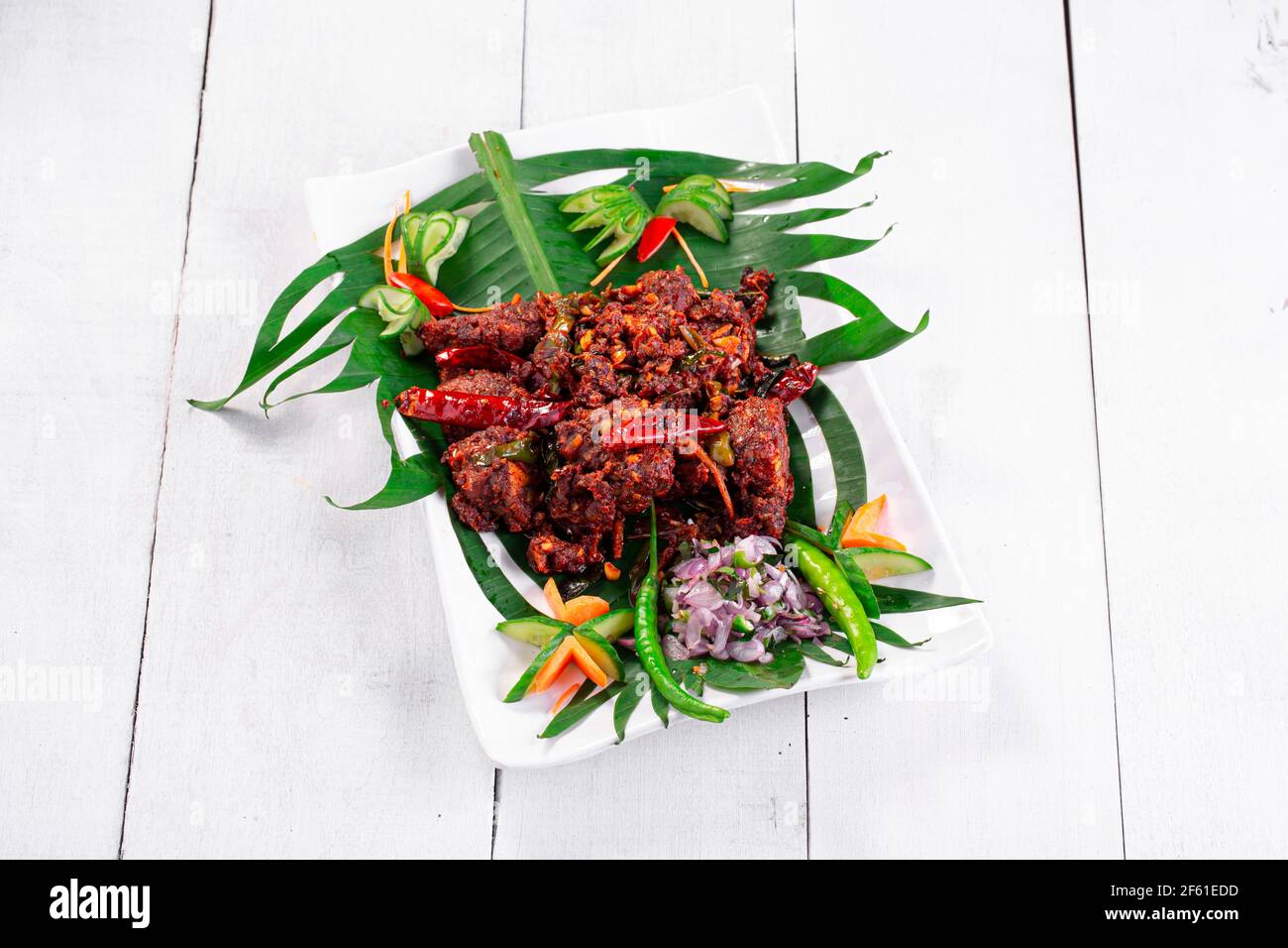 Hühnerperalan oder trockenes Chicken-Kerala-Hühnergericht, das wunderschön in einem weißen Geschirr mit Bananenblatt ausgekleidet ist Stockfoto