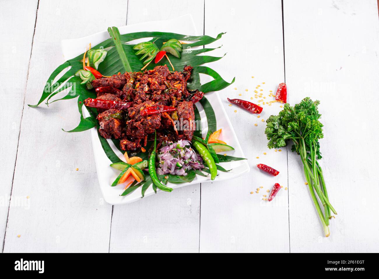 Hühnerperalan oder trockenes Chicken-Kerala-Hühnergericht, das wunderschön in einem weißen Geschirr mit Bananenblatt ausgekleidet ist Stockfoto