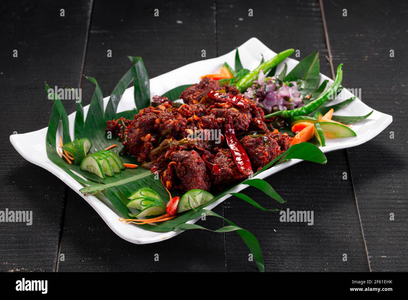 Hühnerperalan oder trockenes Chicken-Kerala-Hühnergericht, das wunderschön in einem weißen Geschirr mit Bananenblatt ausgekleidet ist Stockfoto