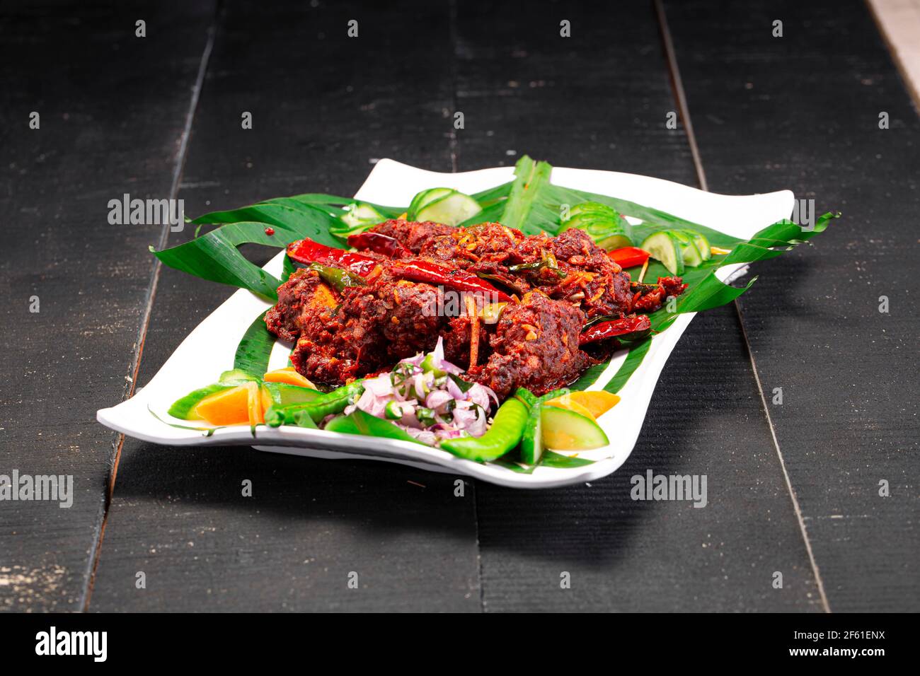 Hühnerperalan oder trockenes Chicken-Kerala-Hühnergericht, das wunderschön in einem weißen Geschirr mit Bananenblatt ausgekleidet ist Stockfoto