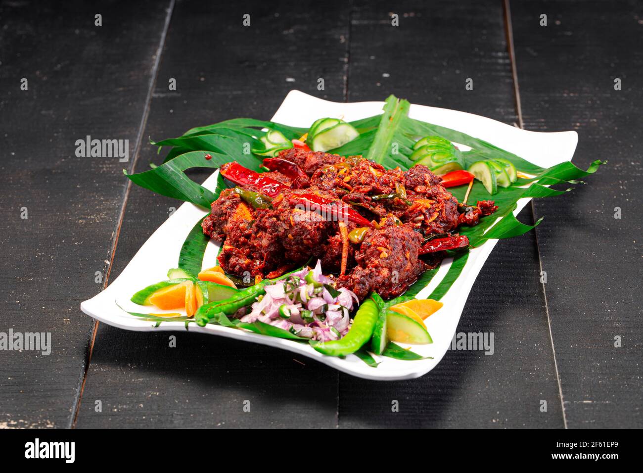 Hühnerperalan oder trockenes Chicken-Kerala-Hühnergericht, das wunderschön in einem weißen Geschirr mit Bananenblatt ausgekleidet ist Stockfoto