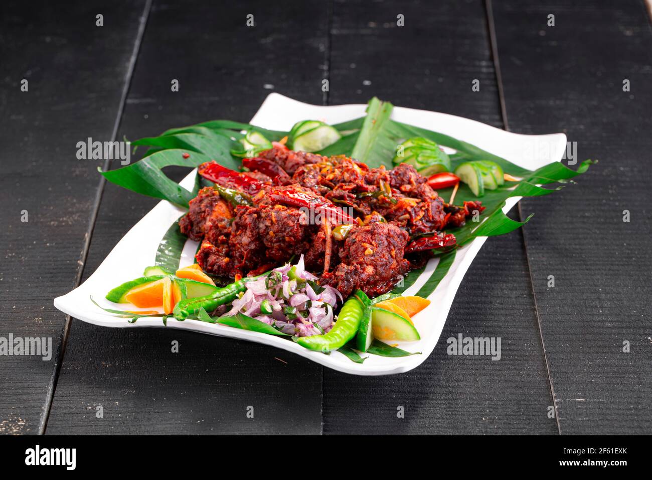 Hühnerperalan oder trockenes Chicken-Kerala-Hühnergericht, das wunderschön in einem weißen Geschirr mit Bananenblatt ausgekleidet ist Stockfoto