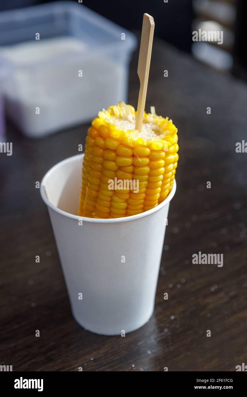 Eine Ähre gekochten Mais in einem Papierbecher. Fast-Food-Konzept. Stockfoto