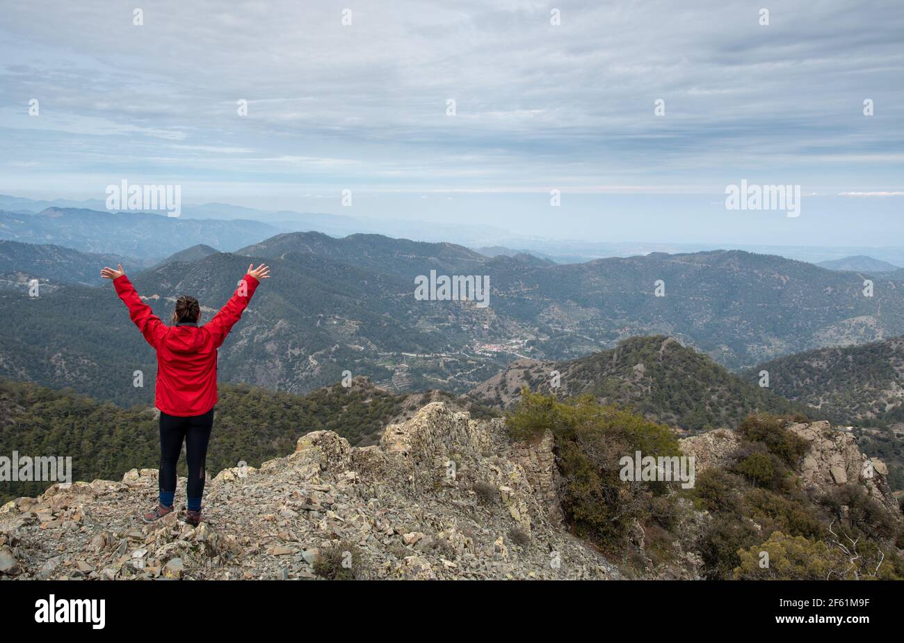 Tourist Frau mit erhobenen Armen auf felsigen Gipfel gegen einen bewölkten Himmel genießen Bergpanorama. Stockfoto