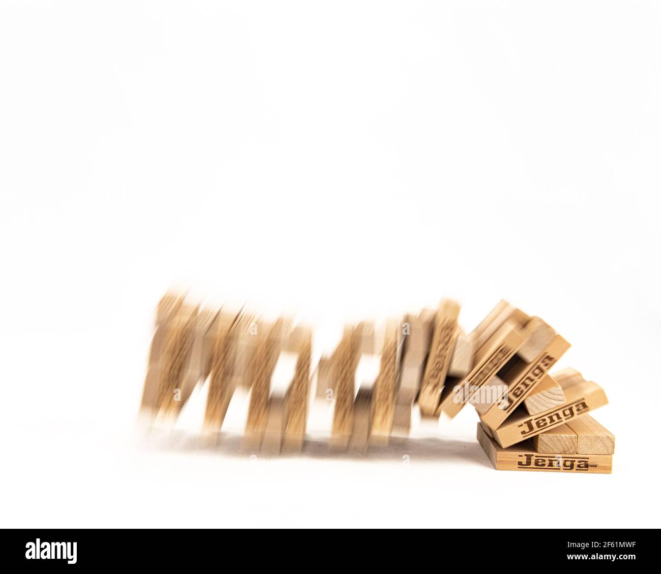 Jenga Tower fällt mit Unschärfe, um Bewegung auf einem zu zeigen Weißer Hintergrund Stockfoto