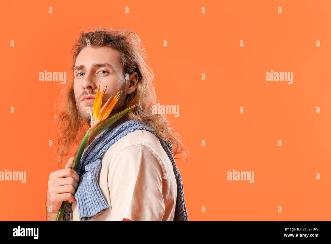 Portrait von schönen jungen Mann mit Blume auf farbigem Hintergrund Stockfoto