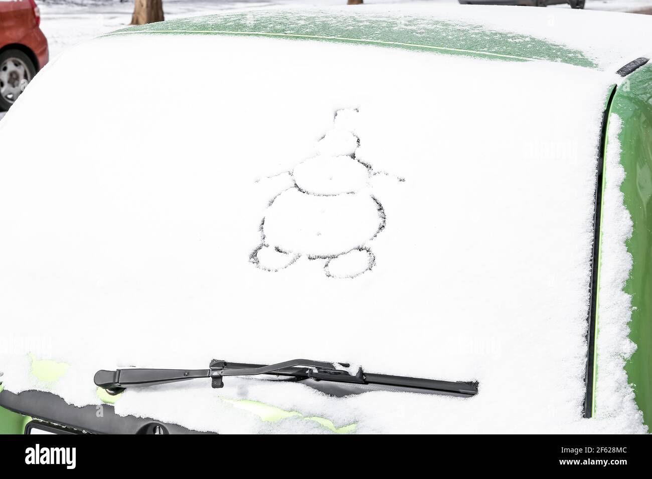 Schneemann auf schneebedeckten Auto gezeichnet Stockfoto