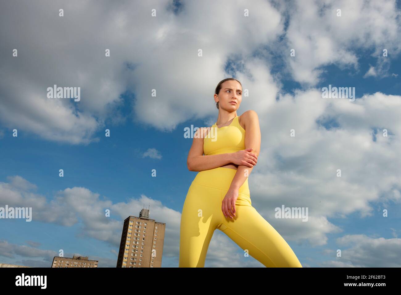 Porträt einer jungen Sportlerin in gelber Sportbekleidung gegen blauen Himmel Stockfoto