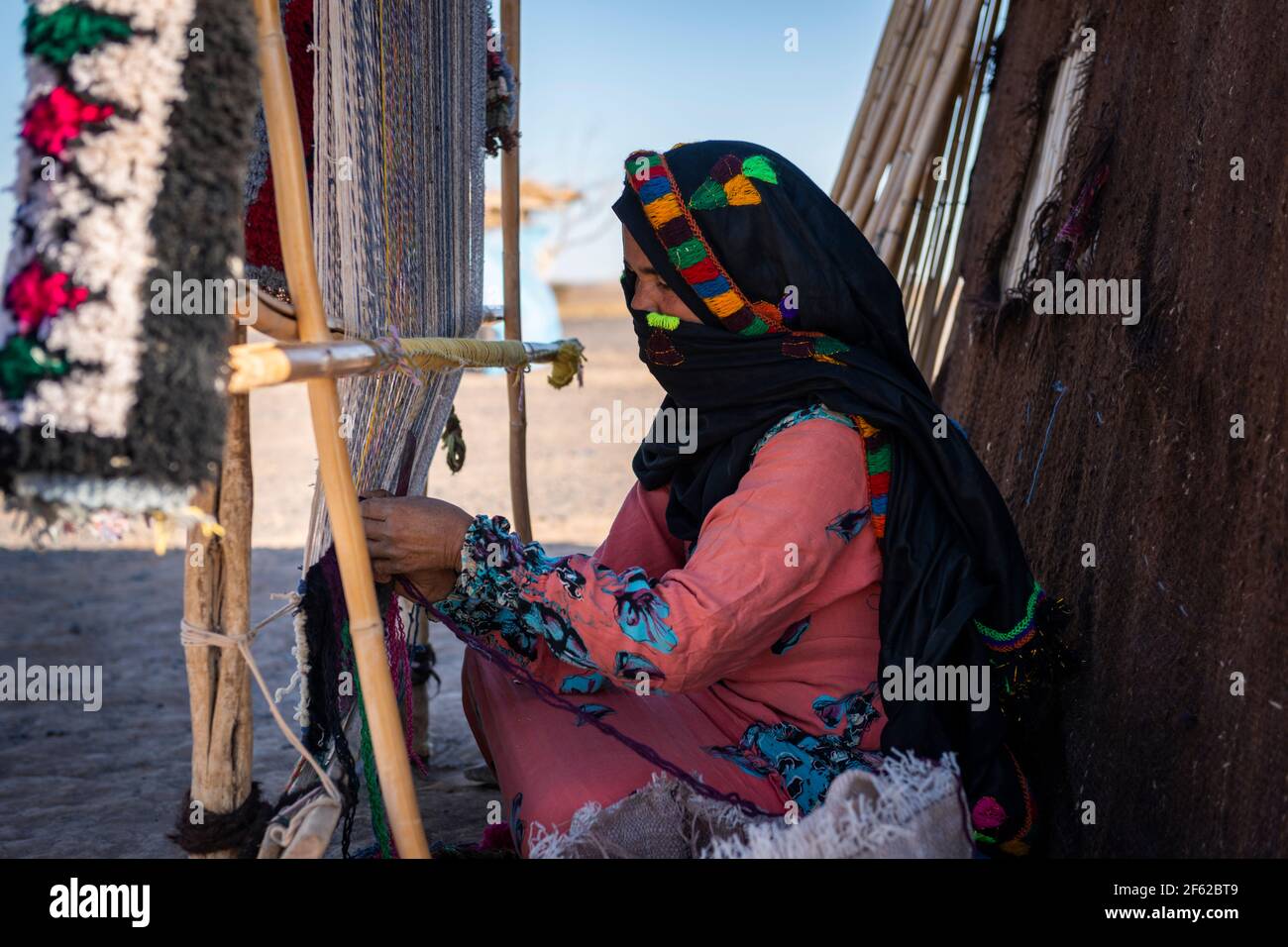 Erg Chebbi, Marokko - 12. April 2016: Eine Berberfrau webt mit einem traditionellen Webstuhl in einem Dorf in der Nähe des Erg Chebbi in Marokko. Stockfoto