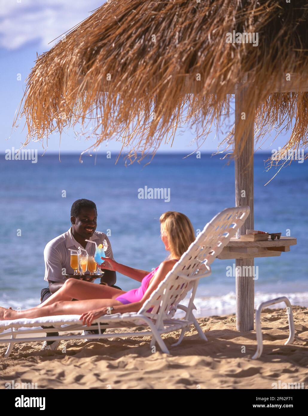Kellner serviert der Frau Cocktails am Strand, Tamarind Cove, Barbados, kleine Antillen, Karibik Stockfoto