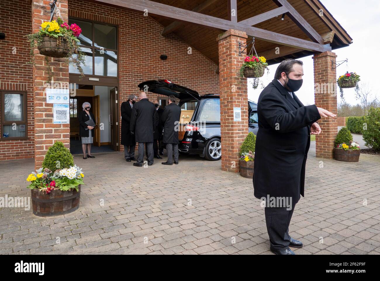 England, Großbritannien. 2021. Bestattungswagen, Sarg, Pallenträger, Bestattungsleiter vor einem Krematorium vor der Krematoriumsfeier während der Coronavirus-Zeit. Stockfoto