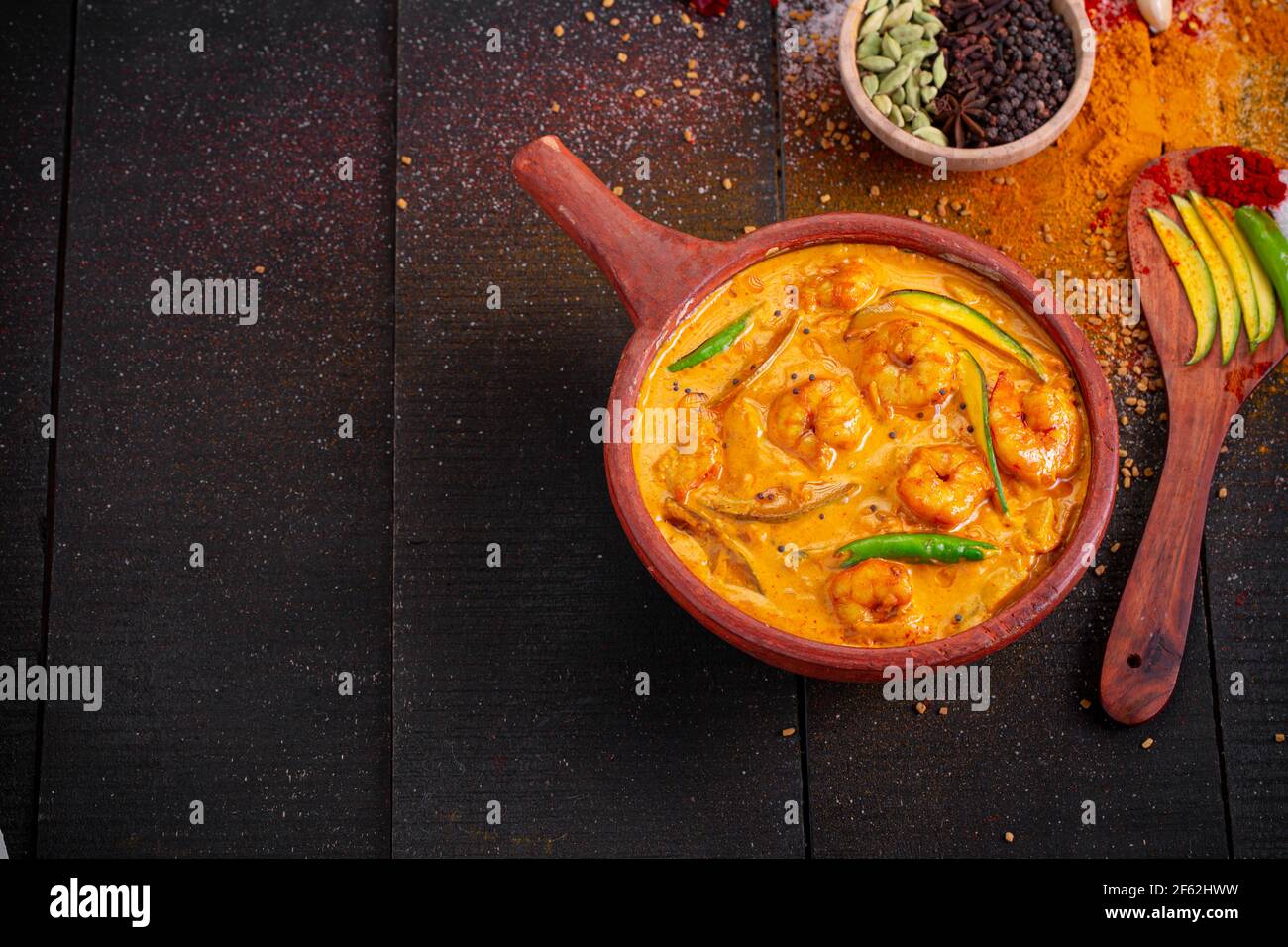 Garnelen Mango Curry, kerala traditionelle Gericht mit roher Mango und Angeordnet in einer irdenen Ware mit schwarzem texturierten Hintergrund Stockfoto