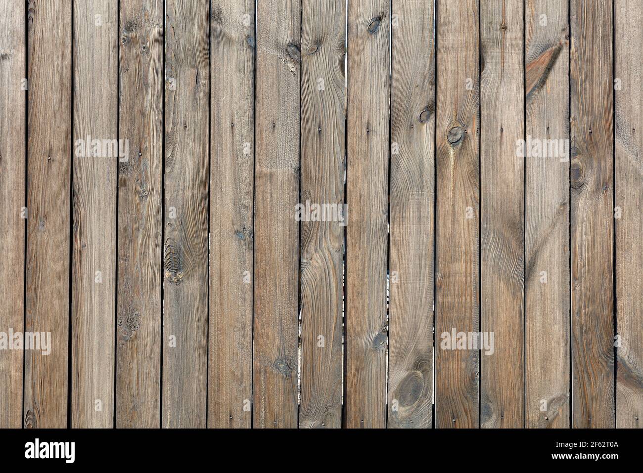 Die Textur eines Holzzauns aus unbemaltem Holz, verwittert, genagelt mit verrosteten Nägeln. Eine hohe Auflösung. Stockfoto