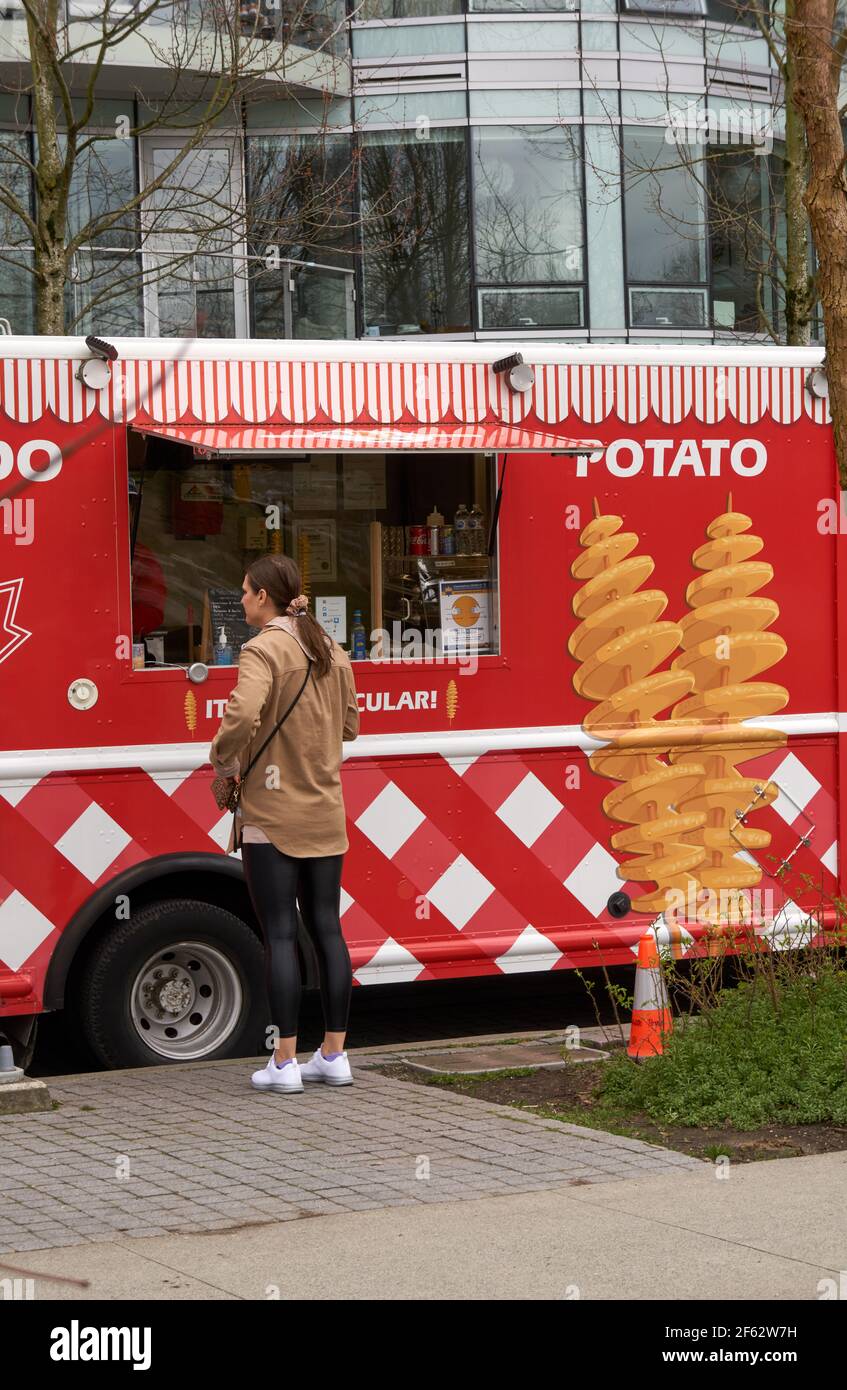Frau, die Lebensmittel von einem Food Truck bestellt, der Spiralkartoffeln verkauft, Vancouver, British Columbia, Kanada Stockfoto