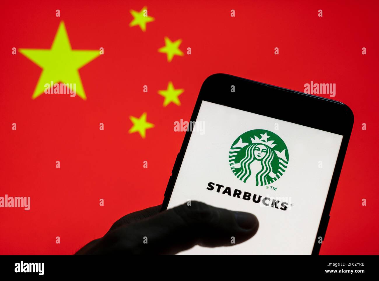 In dieser Abbildung ist das Logo der amerikanischen multinationalen Kette Starbucks Coffee auf einem Android-Mobilgerät mit der Flagge der Volksrepublik China im Hintergrund zu sehen. Stockfoto