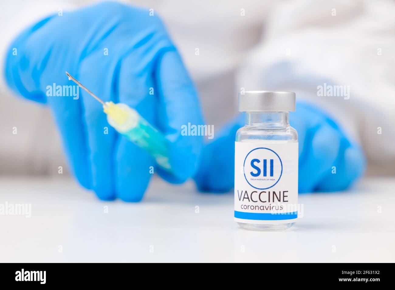 Serum Institute of India SII-Impfstoff gegen Coronavirus und Spritze zur Injektion in die Hand des Gesundheitsarbeiters in Gummihandschuhe und Schutzanzug, März Stockfoto