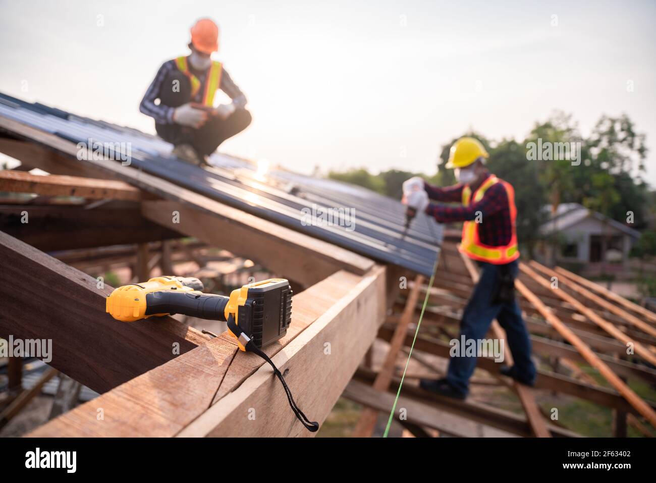 Selektiver Fokus Dachdeckwerkzeuge, Dachdecker Arbeiter mit einem elektrischen Bohrer installieren auf neue Dach Metallblech auf der Baustelle. Stockfoto