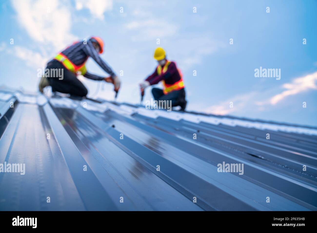 Selektiver Fokus Dach, Bauarbeiter Sicherheitsverschleiß mit elektrischen Bohrwerkzeugen installieren auf neuen Dach Metallblech, Dachkonstruktion Konzept. Stockfoto