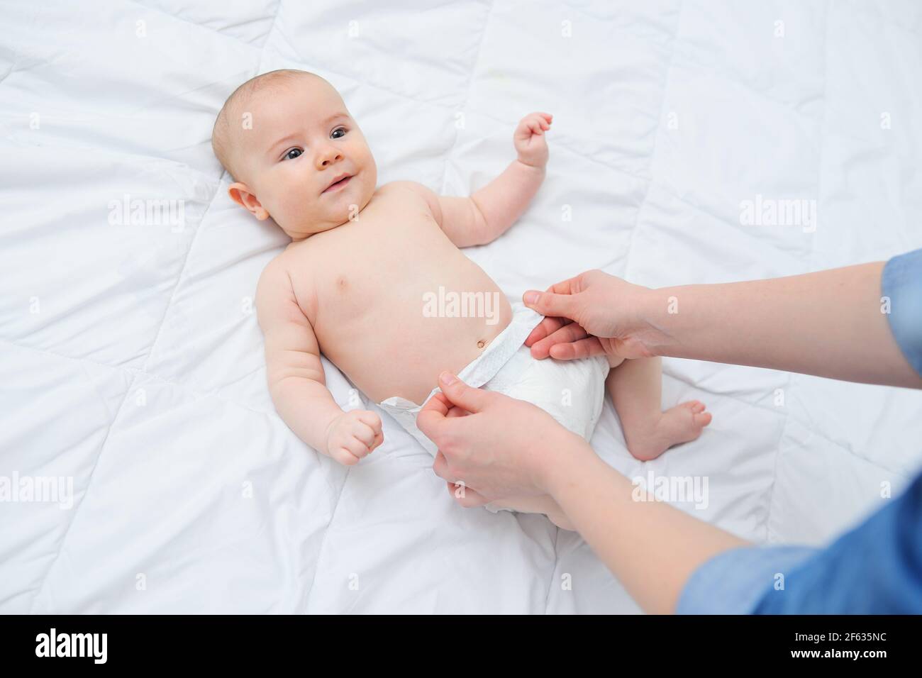 Die Hände der Mutter legen die Windel des Babys an. Stockfoto