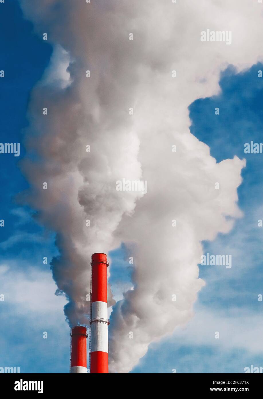 Umweltverschmutzung, Umweltproblem, Rauch aus dem Schornstein einer Industrieanlage oder thermisches Kraftwerk auf einem Hintergrund des blauen Himmels mit Stockfoto