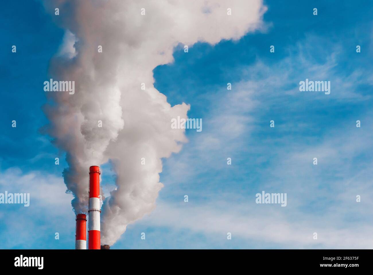 Umweltverschmutzung, Umweltproblem, Rauch aus dem Schornstein einer Industrieanlage oder thermisches Kraftwerk auf einem Hintergrund des blauen Himmels mit Stockfoto
