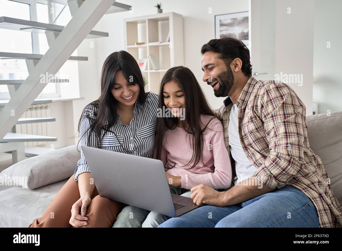 Glückliche indische Familie mit Teenager-Tochter Spaß mit Laptop zu Hause. Stockfoto