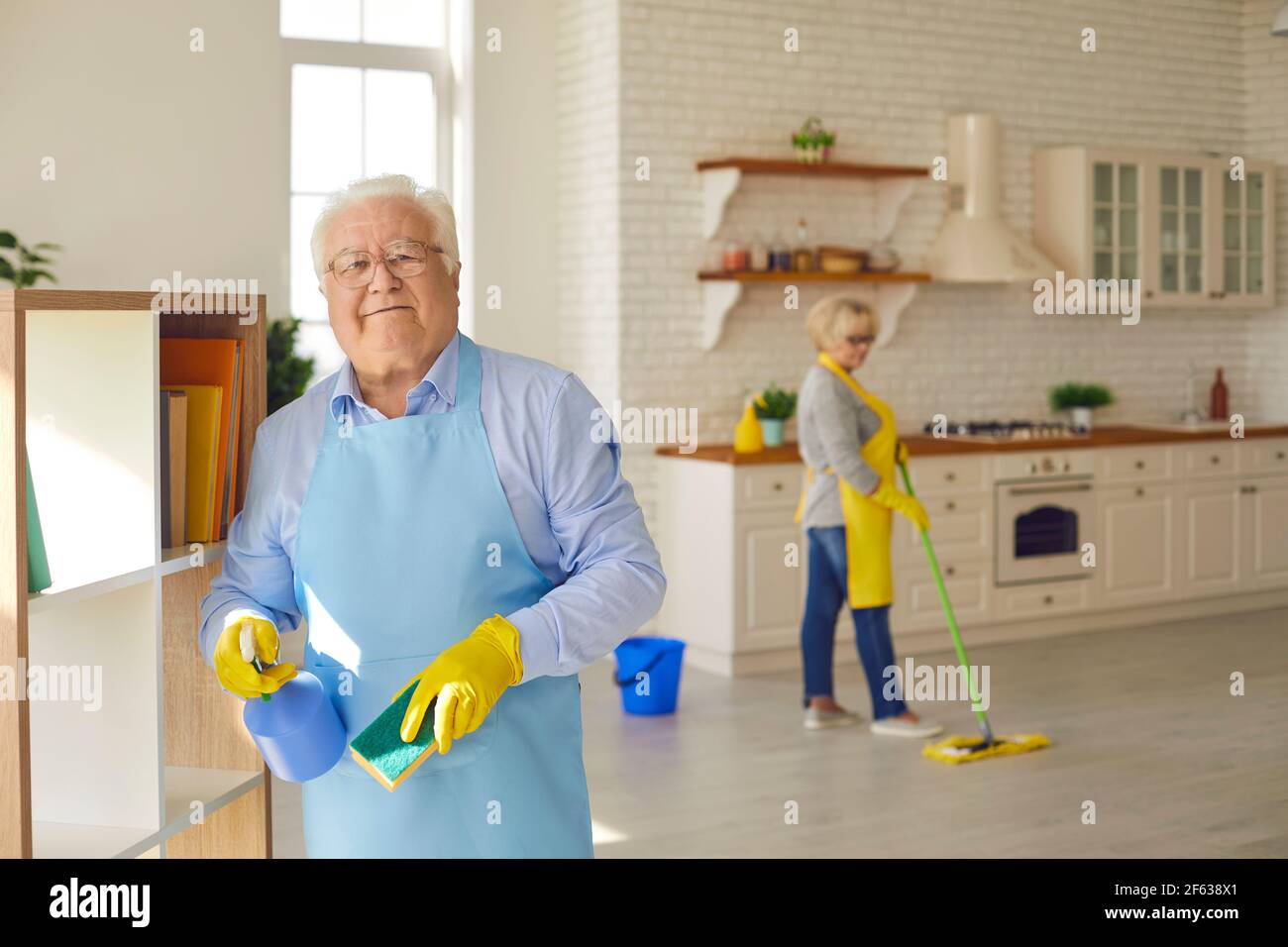Der ältere Mann wischt die Regale mit einem Waschlappen und Waschmittel,  während seine Frau den Boden wäscht Stockfotografie - Alamy