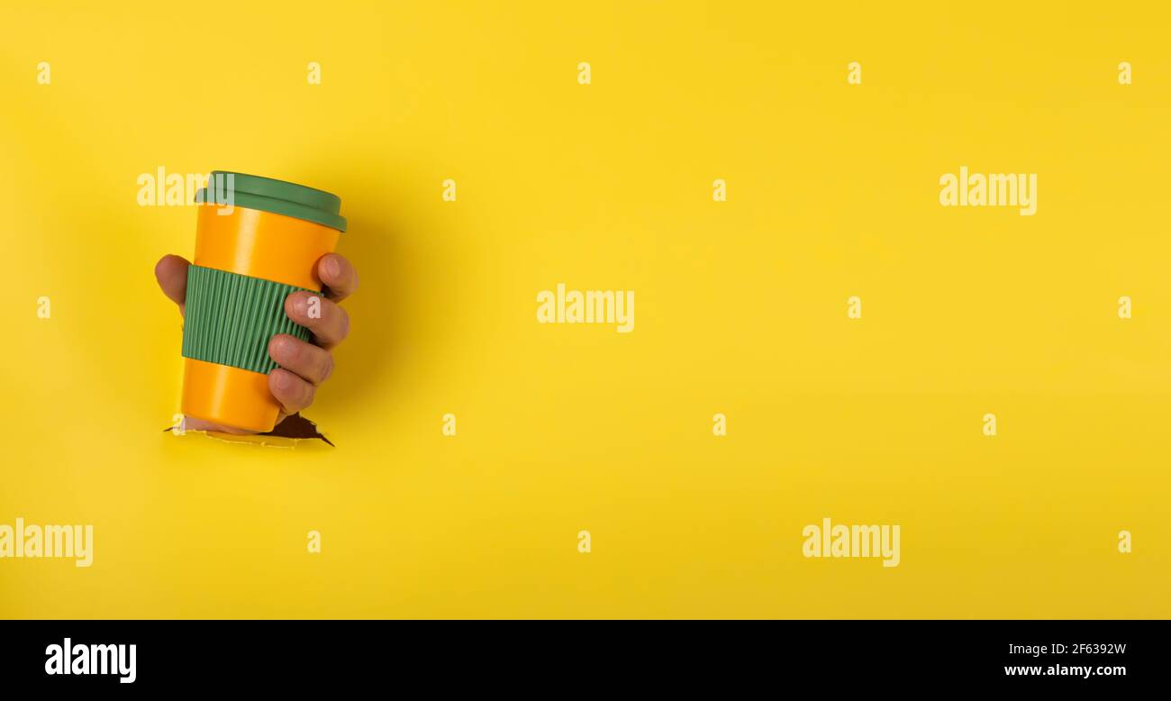 Halten Sie eine wiederverwendbare Kaffeetasse mit dem Deckel fest Geschlossen auf gelbem Hintergrund mit Platz für Text Stockfoto