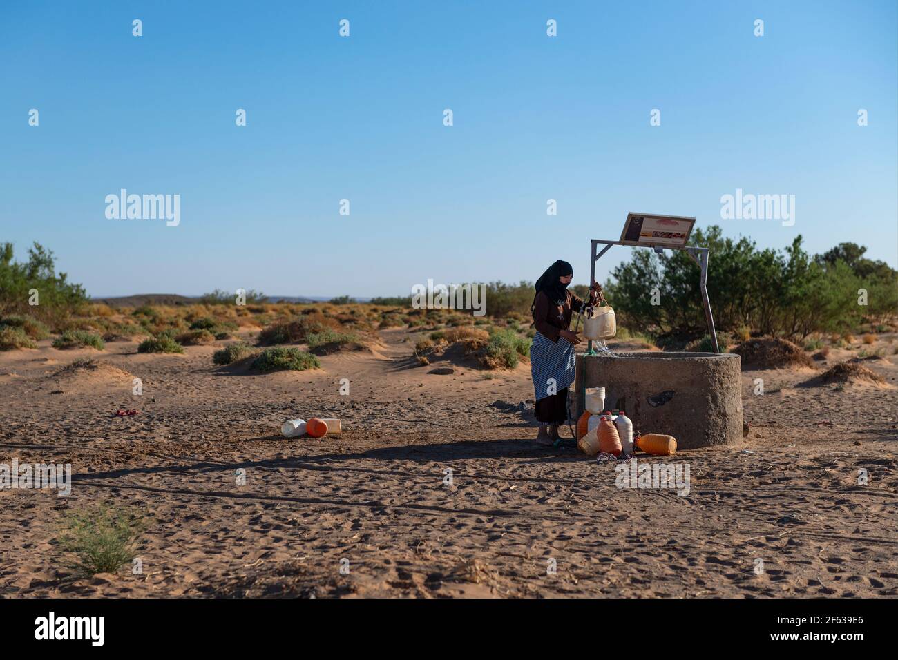 Erg Chebbi, Marokko - 12. April 2016: Eine Berberfrau sammelt Wasser aus einem Brunnen in Erg Chebbi, Marokko. Stockfoto