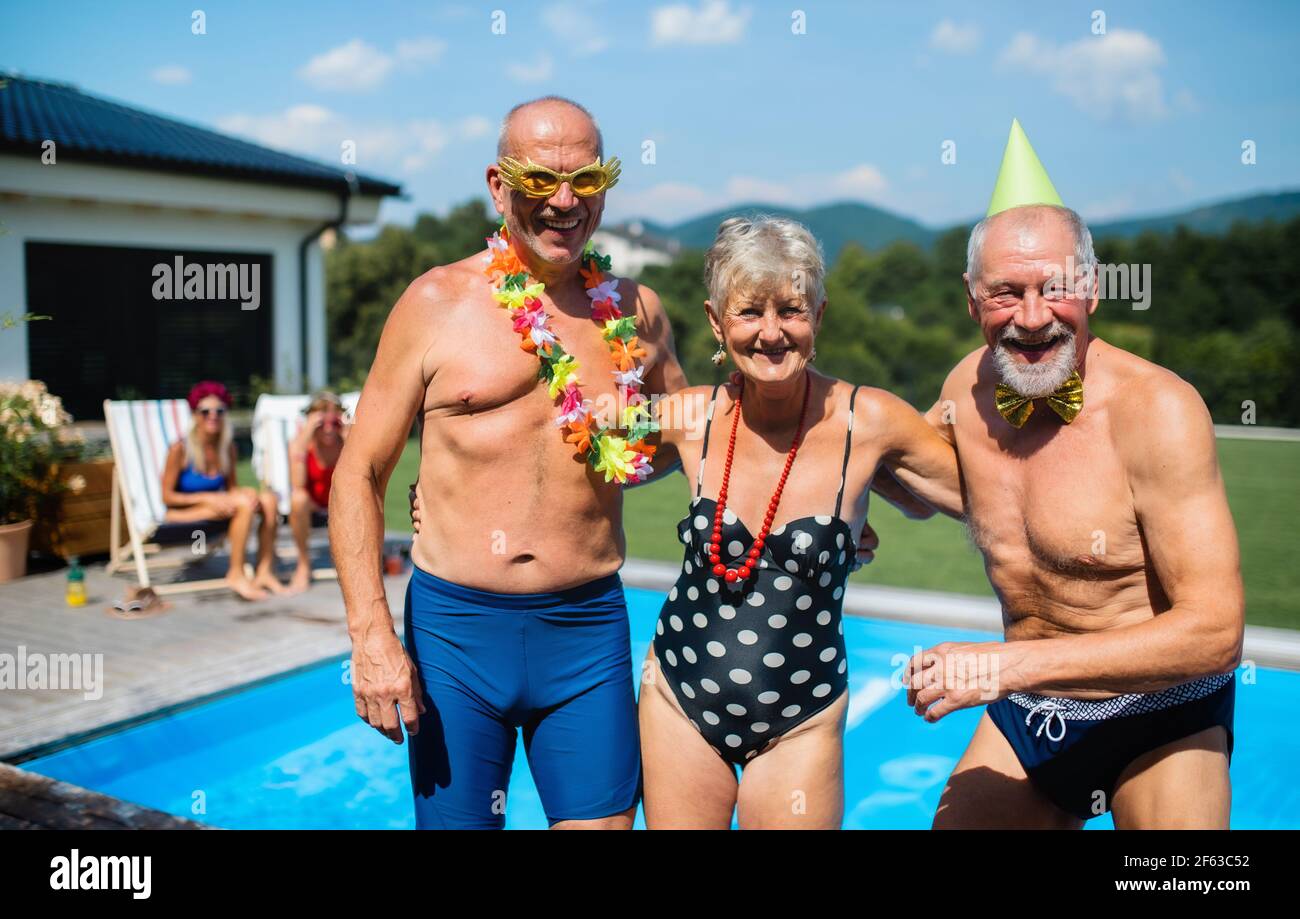 Gruppe von fröhlichen Senioren durch Schwimmbad im Freien im Hinterhof, mit Partei. Stockfoto