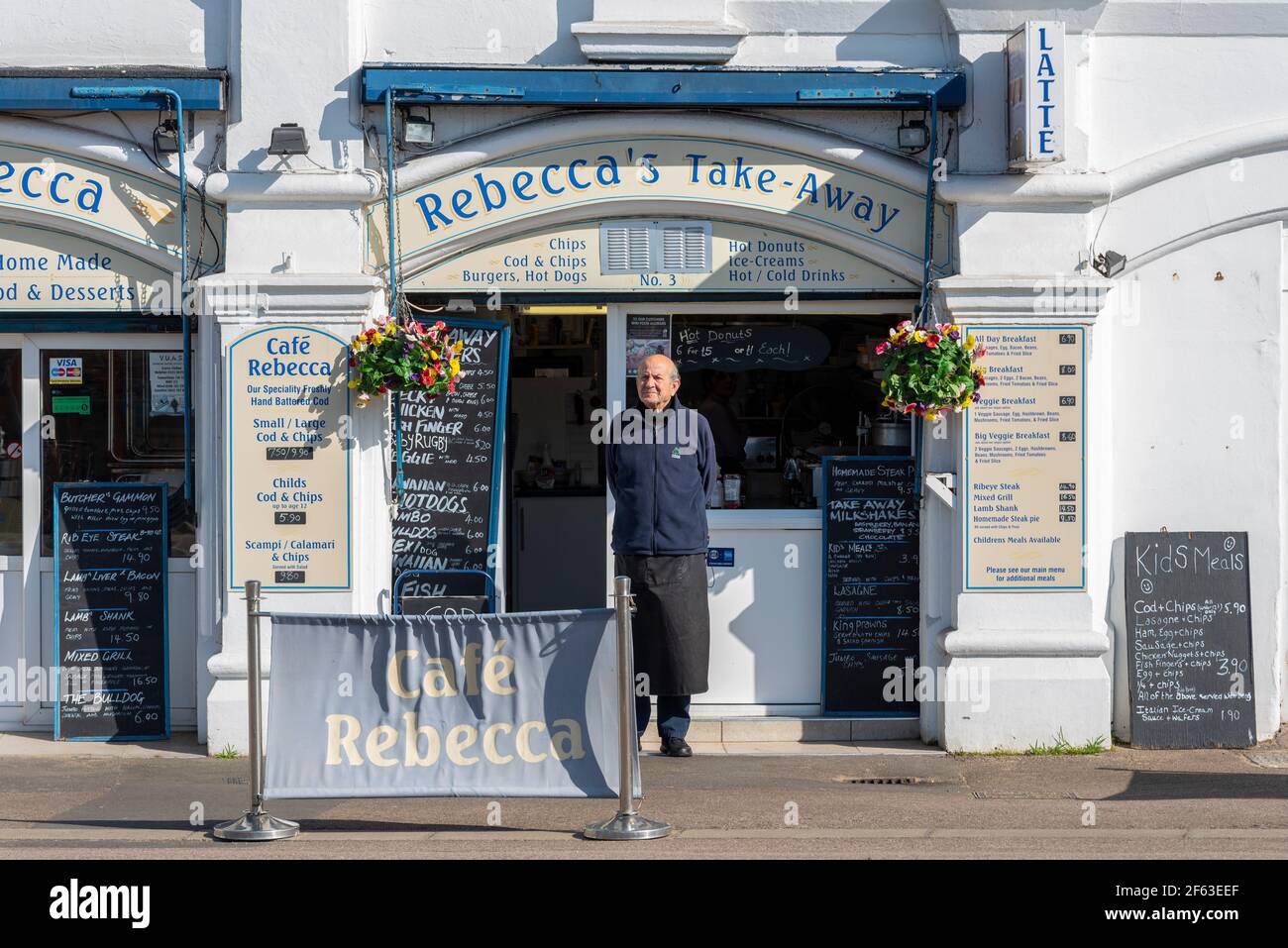 Männlicher Besitzer oder Mitarbeiter, der vor Rebecca's Take Away Café in Southend on Sea, Essex, Großbritannien, auf Kunden wartet. Lockdown lockert den Tag. Hospitality-Arbeit Stockfoto