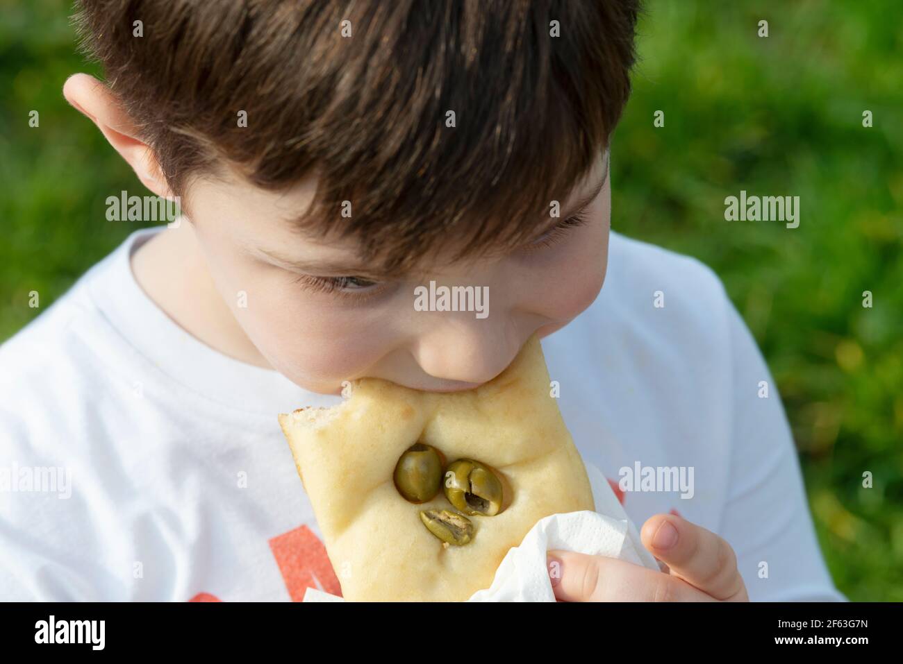 Junger Junge essen Brot whit Olive Stockfoto