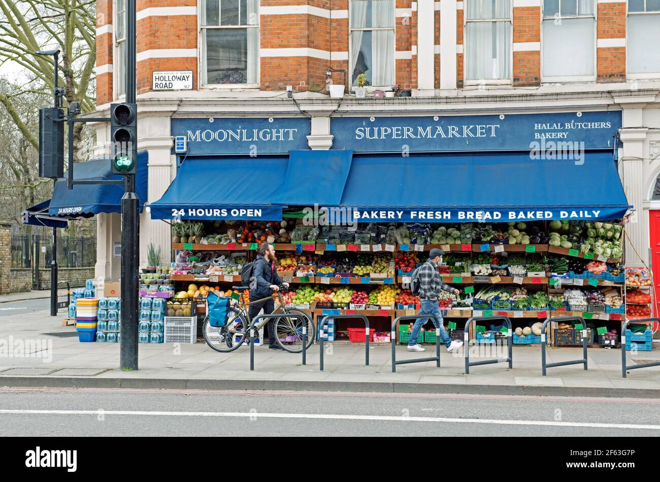 Moonlight Supermarkt mit Obst und Gemüse auf der Ausstellung Leute einschließlich Radfahrer vorbei, Holloway Road, London Borough of Islington. Stockfoto