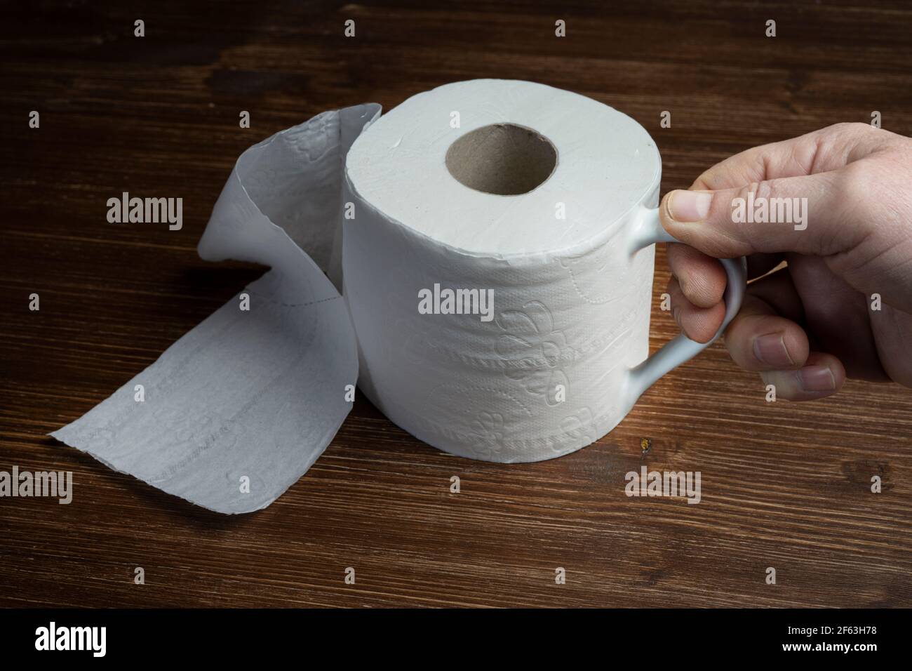 Eine Rolle Toilettenpapier, die als Tasse verwendet wird Ein Holztisch Stockfoto