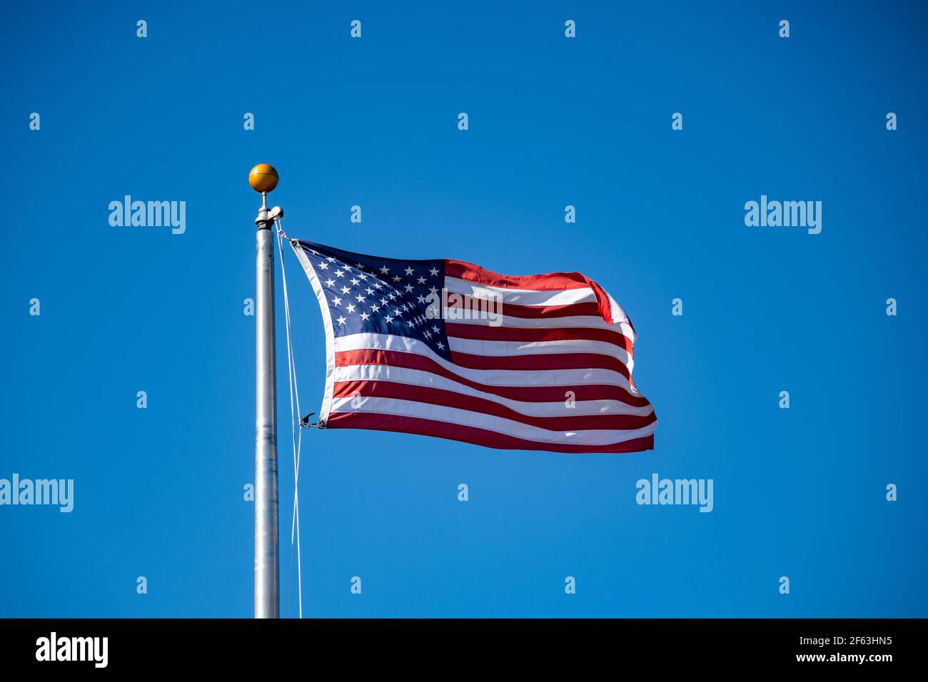 Eine amerikanische Flagge winkt in der Brise gegen einen klaren Blauer Himmel Stockfoto