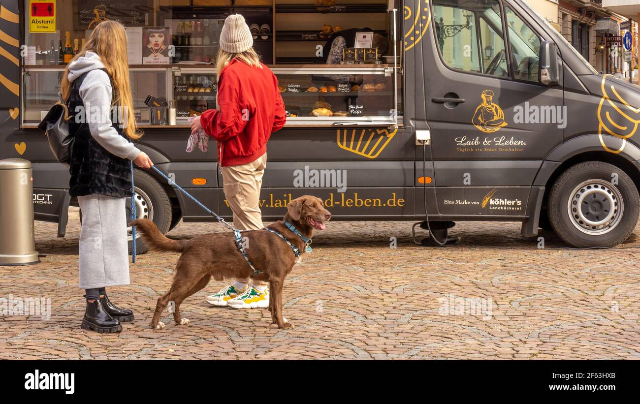 Zwei junge Frauen mit Hund vor der mobilen Gourmet-Station 'Power Pretzel' kaufen Take-Away-Lebensmittel in Sperrzeit, da Restaurants geschlossen sind. Stockfoto