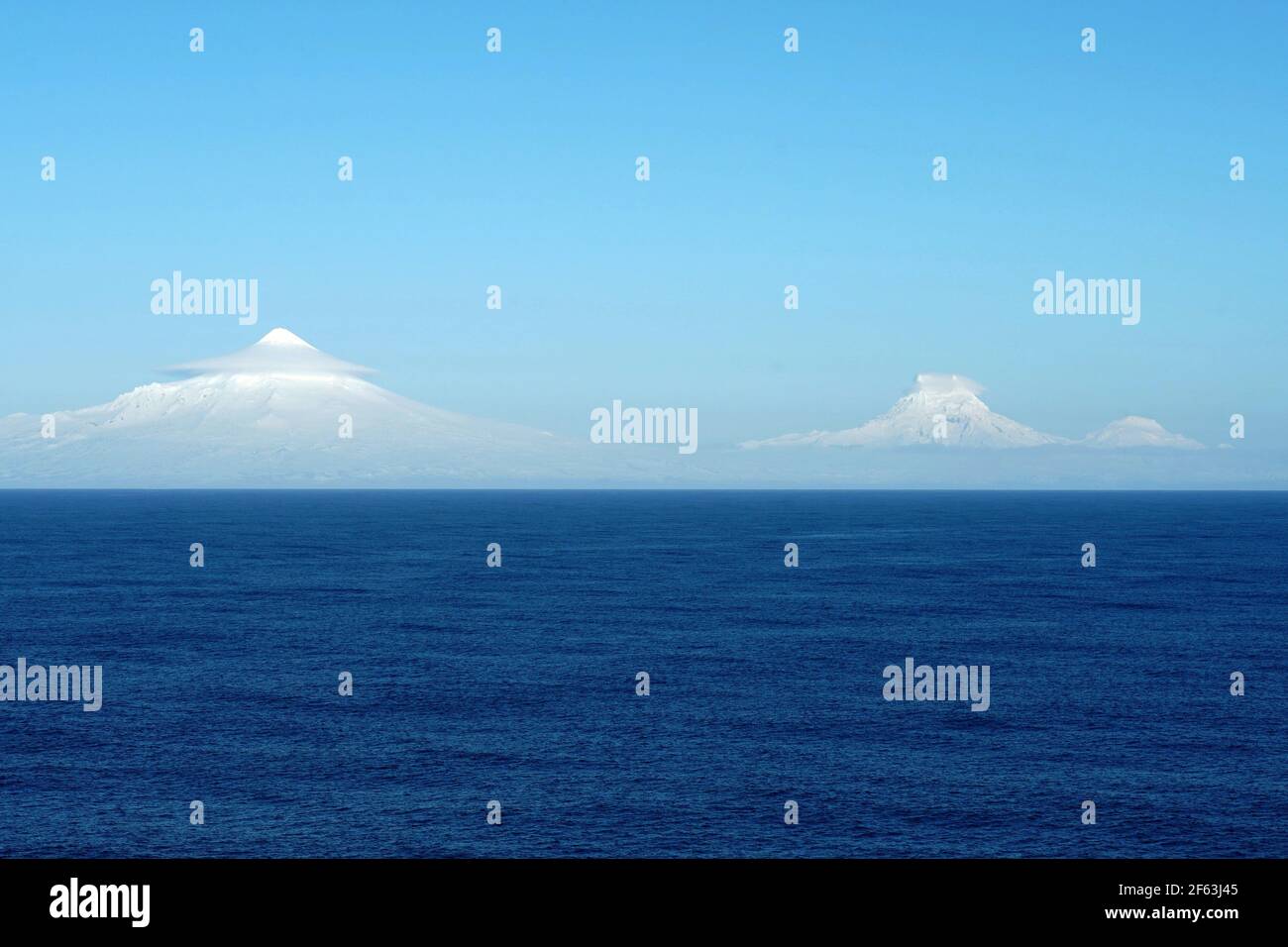 Berge, die auf den Aleutischen Inseln als Teil der Inselkette in Alaska von Wolken bedeckt sind und von Schiffen beobachtet werden, die über den Pazifischen Ozean segeln. Stockfoto