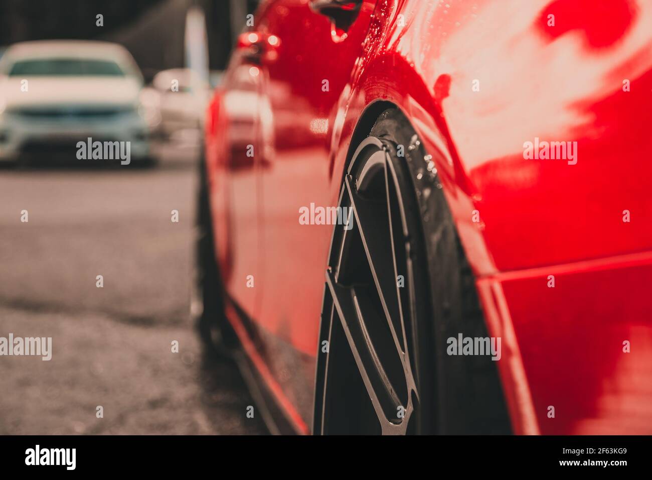 Linke Seite eines roten Sportwagens. Radhäuser aus nächster Nähe. Teil der Leichtmetallfelgen. Details und Ausstattung. Stockfoto