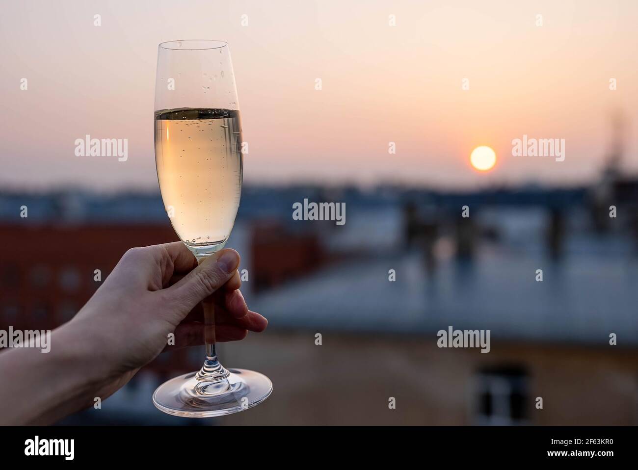 Mädchen hält ein Glas Champagner in den Sonnenuntergang. Stockfoto