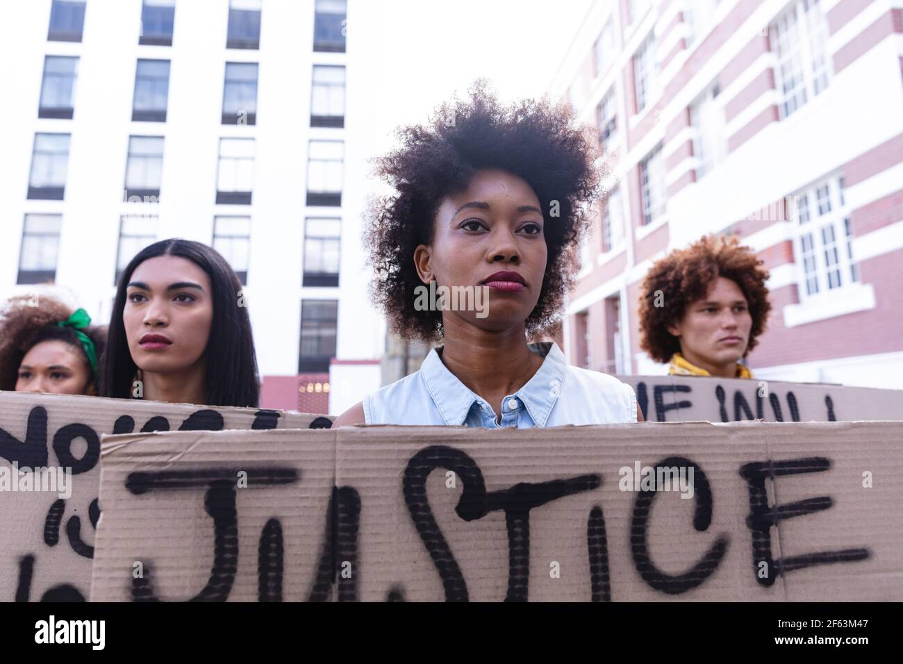 Drei verschiedene männliche und weibliche Demonstranten hielten am märz selbstgemachte Protestschilder blicken weg Stockfoto