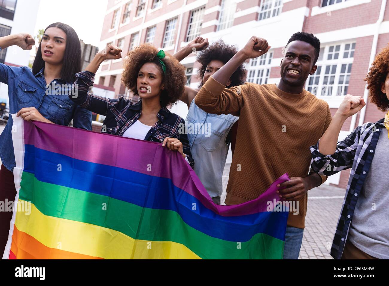 Verschiedene männliche und weibliche Demonstranten hielten am marsch Regenbogenfahne, riefen und rafften Fäuste Stockfoto