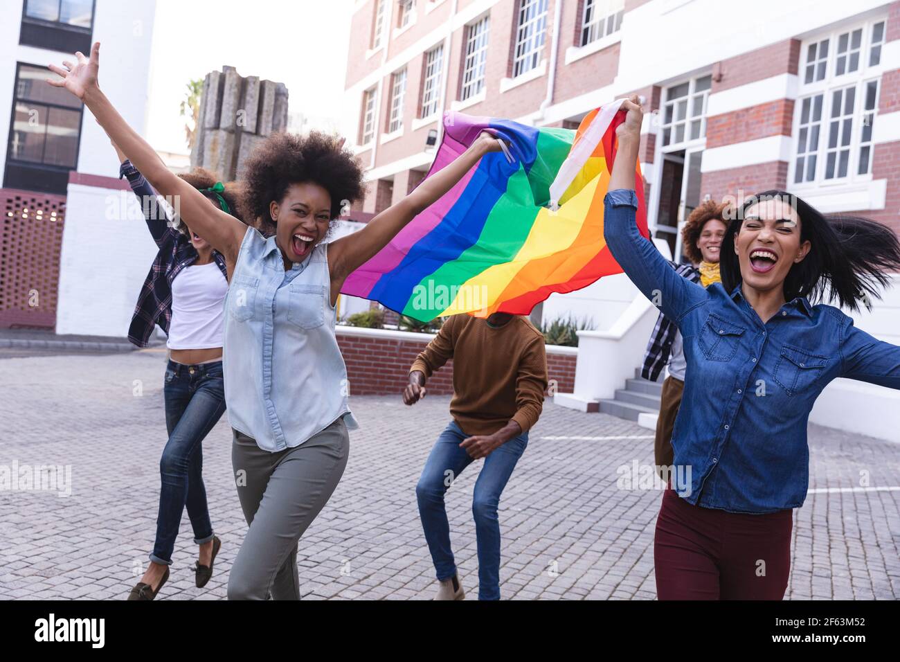 Verschiedene männliche und weibliche Demonstranten hielten am märz Regenbogenfahne in der Hand und jubelten mit erhobenen Waffen Stockfoto