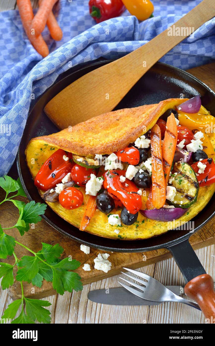 Omelette im griechischen Stil mit gegrilltem Gemüse und Feta-Käse serviert In einer Pfanne Stockfoto