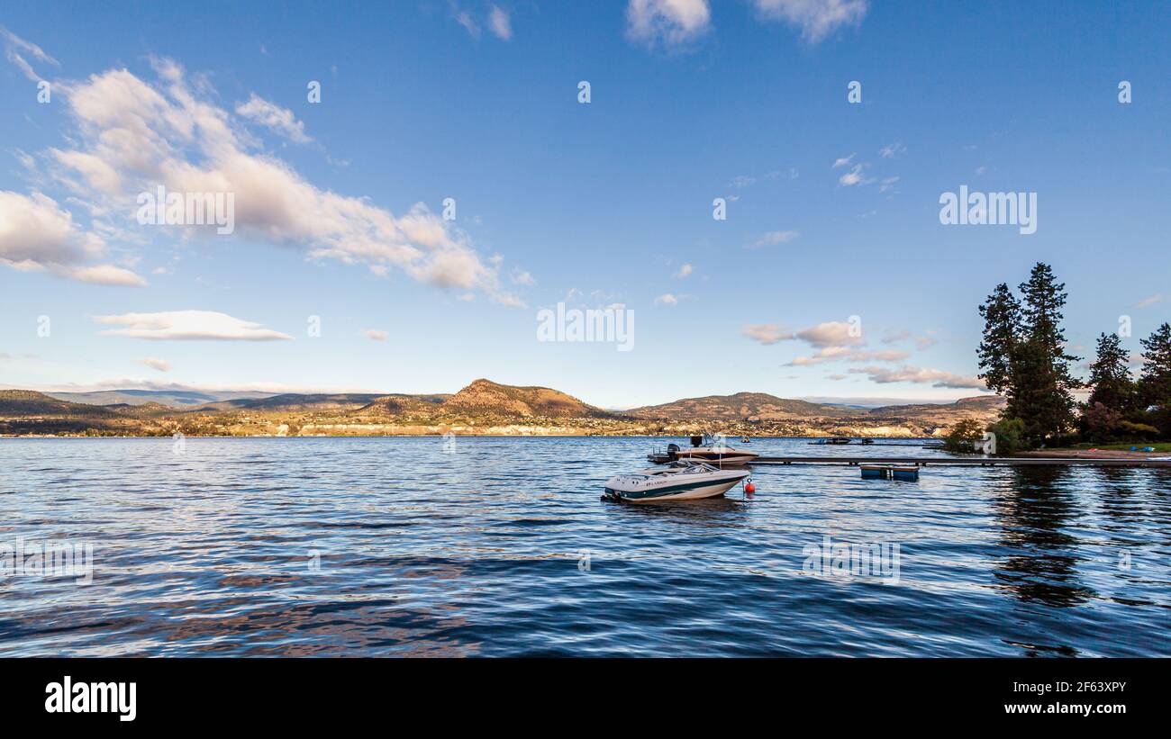 NARAMATA, KANADA - 4. JULI 2020: Motorboote am morgendlichen Sommersee blauer Himmel und weiße Wolken Stockfoto