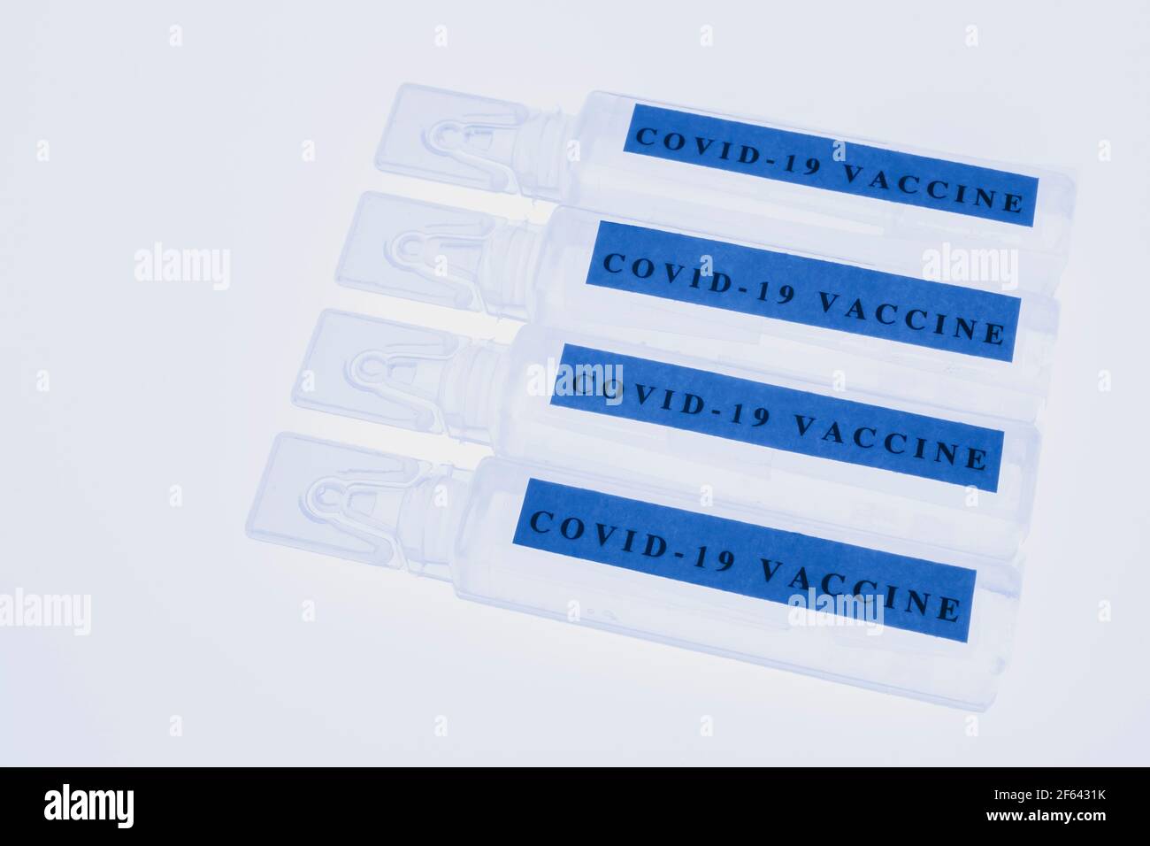 Blaue Fläschchen mit Covid-19-Impfstoff auf weißem, durchscheinendem Hintergrund Stockfoto