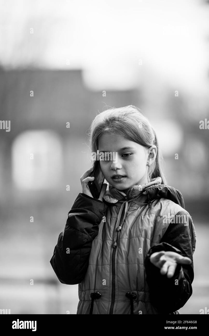 Kleines Mädchen im Freien auf einem Handy reden. Schwarzweiß-Foto. Stockfoto