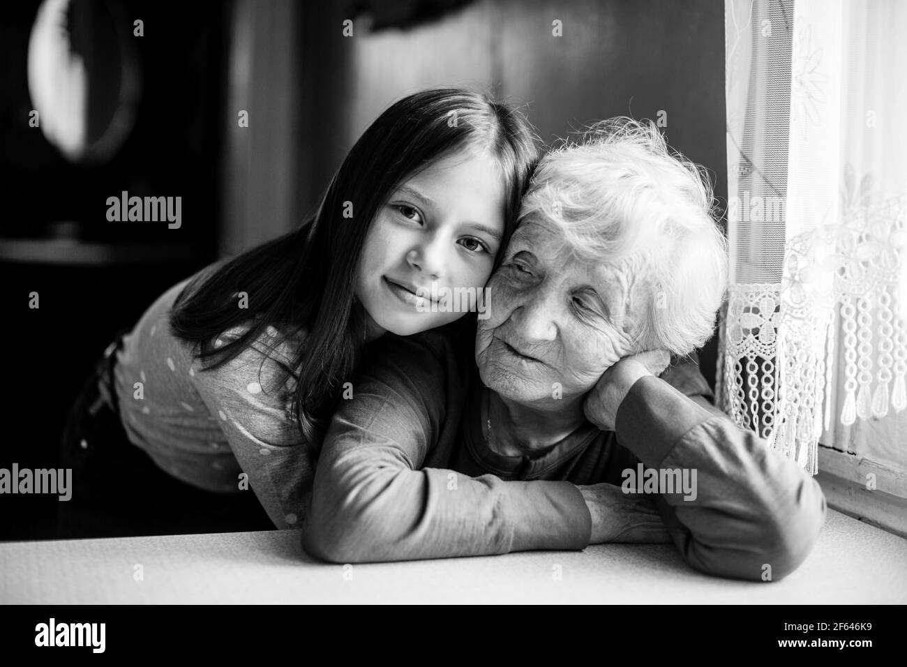 Kleines Mädchen umarmt ihre Großmutter. Schwarz-Weiß-Porträt. Stockfoto